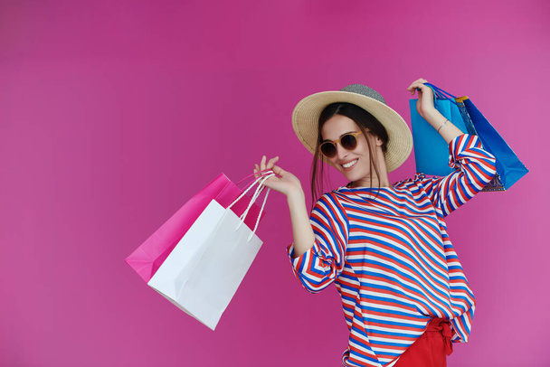 Junge Frau mit Einkaufstaschen auf rosa Hintergrund. Glückliches Mädchen posiert nach einem Tag großen Verkaufs mit neuen Einkäufen. Black Friday-Konzept - Foto, Bild