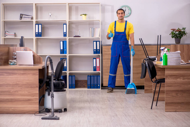 Joven contratista masculino limpiando la oficina - Foto, imagen