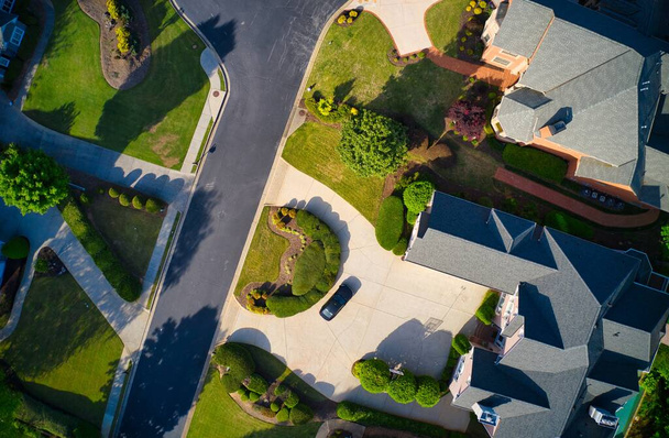 Vista dall'alto verso il basso di belle case, tetti e lussureggianti giardini verdi in una suddivisione di lusso nei sobborghi degli Stati Uniti girato durante l'ora d'oro durante l'inizio della primavera. - Foto, immagini