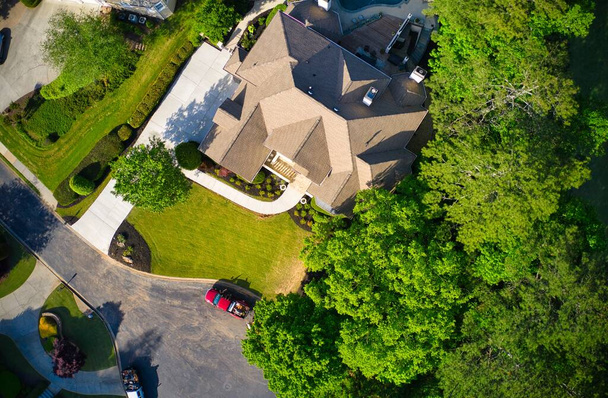 Vista de arriba hacia abajo de hermosas casas, techos y exuberantes patios verdes ajardinados en una subdivisión de lujo en los suburbios de EE.UU. filmado durante la hora dorada a principios de primavera. - Foto, Imagen