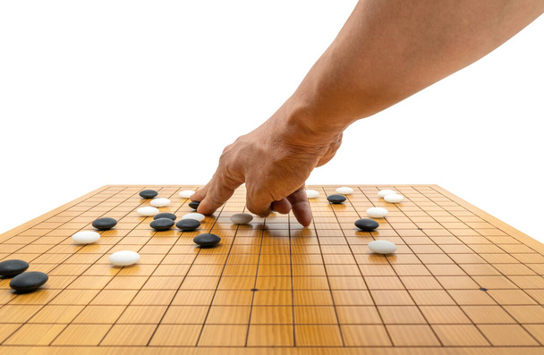 Hand spelen bordspel van Go of Japans schaakbordspel, gebruik zwarte stenen en witte stenen om territorium te creëren en de tegenstander te vangen. Geïsoleerde afbeelding op witte achtergrond. - Foto, afbeelding