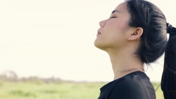 Ritratto ravvicinato di giovane ragazza asiatica rilassata godendo di un tramonto tranquillo e guardando verso l'alto espirando aria fresca rilassarsi in un parco pubblico sul bellissimo tramonto estivo. - Filmati, video