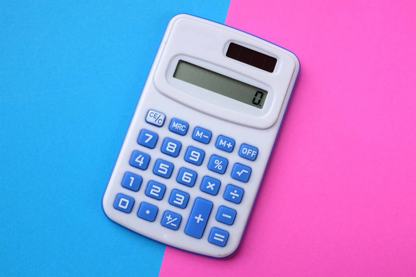 Une calculatrice bleue sur le fond bleu et rose à deux tons - Photo, image