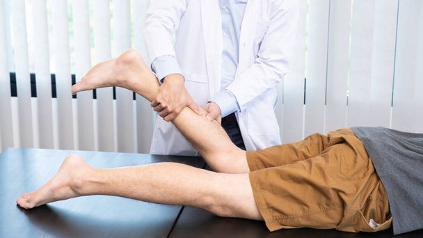 Conceito médico um médico masculino diagnosticando a perna de um paciente masculino pressionando a perna por causa de jogar futebol. - Foto, Imagem