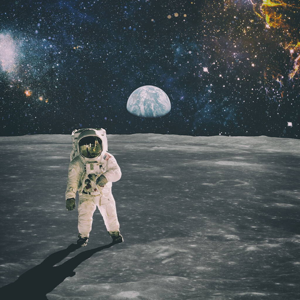 Астронавт смотрит на инопланетное солнце, которое освещает бесплодный мир, в котором он стоит. Элементы этого изображения предоставлены НАСА - Фото, изображение