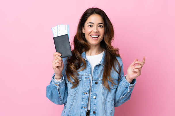 Woman over isolated blue background happy in vacation with passport and plane tickets - Photo, Image
