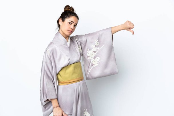 Nainen yllään kimono yli eristetty tausta osoittaa peukalo alaspäin negatiivinen ilme - Valokuva, kuva