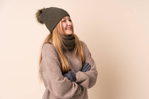 Teenager Ukrainian girl with winter hat isolated on beige background looking to the side - Foto, Imagem