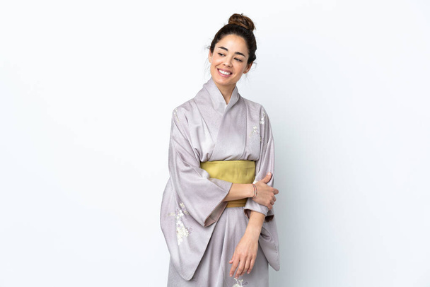 Kobieta ubrana w kimono na odosobnionym tle spogląda w bok i uśmiecha się - Zdjęcie, obraz