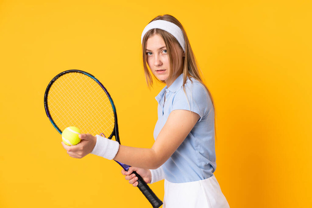 Teenager Ukrainian girl tennis player isolated on yellow background playing tennis - Фото, зображення