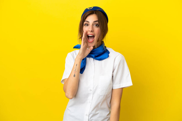 Airplane stewardess woman isolated on yellow background shouting with mouth wide open - 写真・画像