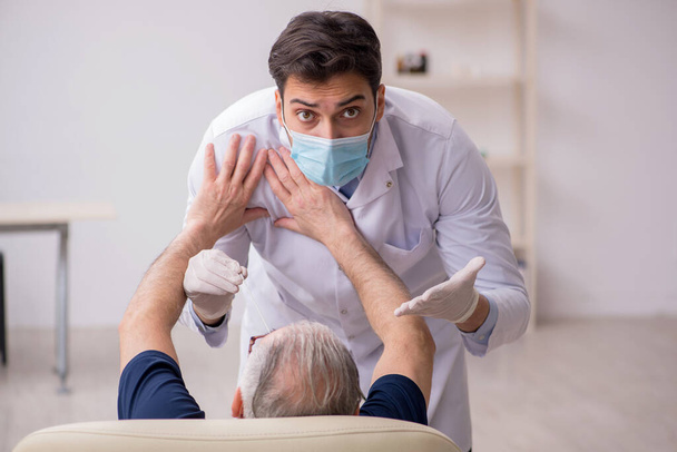 Paciente do sexo masculino velho visitando jovem médico otorrinolaringologista - Foto, Imagem