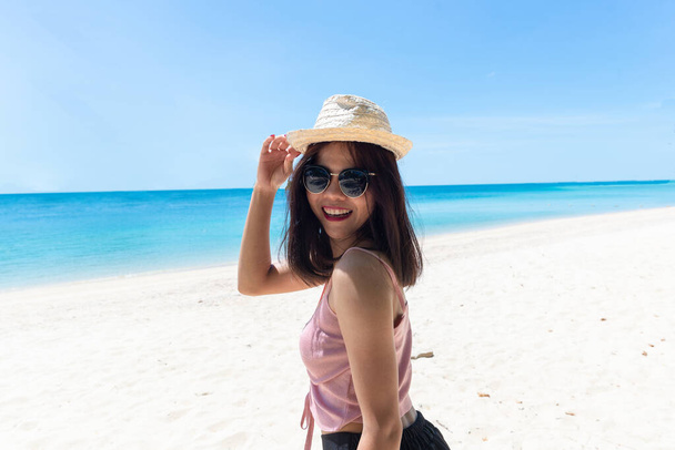Egy fiatal nő arca rózsaszín tanksapkában, napszemüvegben. Boldog nő mosolyog a nyári vakáció alatt a tengeren. Gyönyörű hölgy pihent a tengerparton. friss ég. Nyaralás, trópusi, kényelmes - Fotó, kép