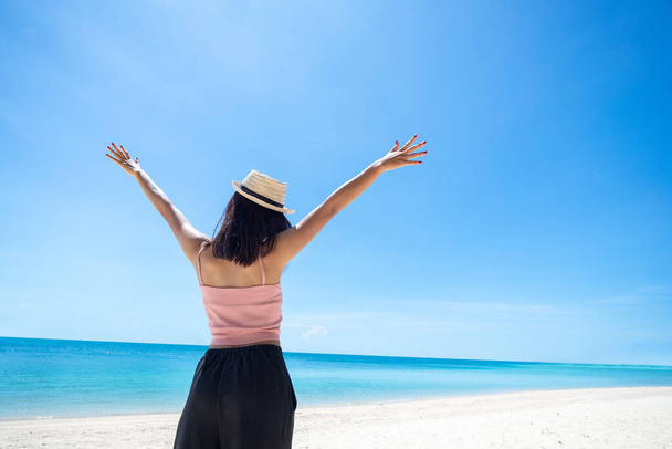 woman tan skin wearing pink tank top and straw hat with standing arms outstretched on sky. looking into the sea and fresh sky. Summer travel. Relax, Holiday and tropical, comfortable concept. - Foto, immagini
