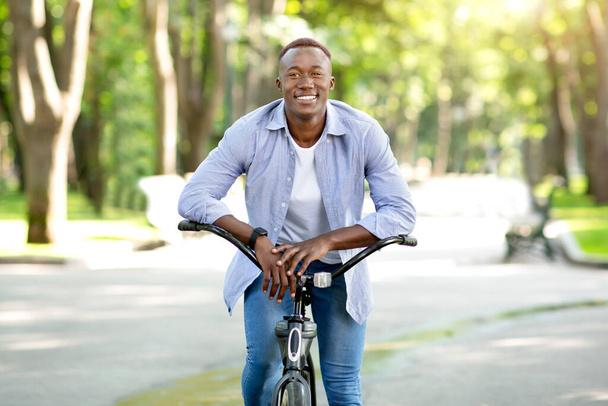 都市の冒険の概念。ハッピーアフリカ系アメリカ人男上の楽しい自転車に乗る上の都市公園 - 写真・画像