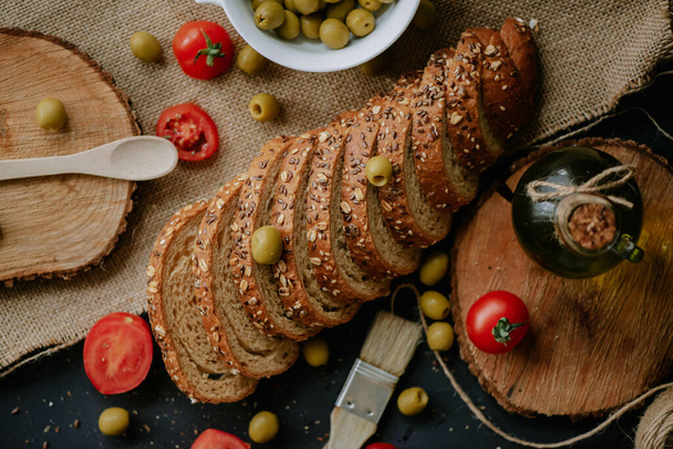 A top view of whole grain wheat bread with tomatoes and green olives - Foto, afbeelding