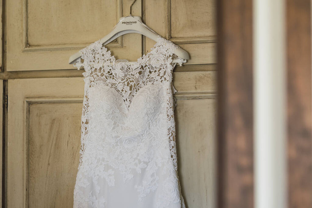 A closeup of a white lace wedding dress on the hanger - Фото, изображение
