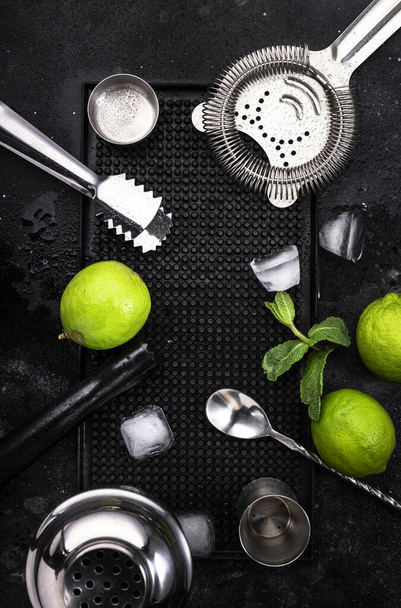 Mojito cocktail alcohol long drink making. Mint, lime, ice, white rum, cane sugar ingredients and bar utensils. Top view, white table background. Flat lay - Foto, Bild