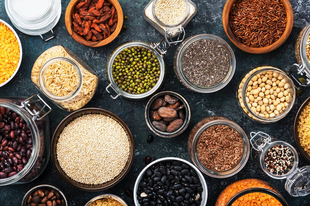 Various organic superfoods, beans, grains, cereals, legumes, seeds in reusable cans and jars. Copy space top view. Blue background - Fotoğraf, Görsel