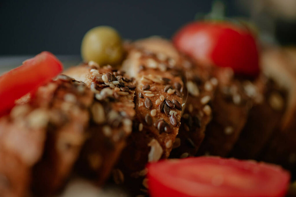 A selective focus shot of whole grain wheat bread with tomatoes and green olives - Foto, Imagem