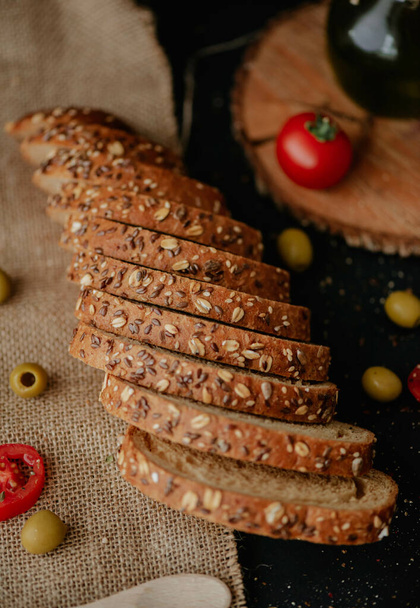 A top view of whole grain wheat bread with tomatoes and green olives - Photo, image