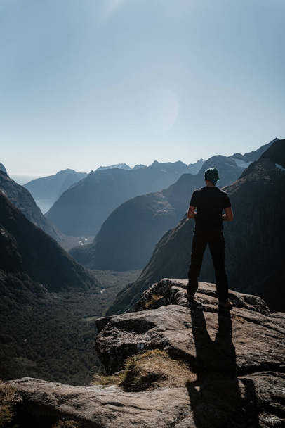 A back view of a man admiring the Gertrude Saddle route in Fiordland national park, New Zealand - 写真・画像
