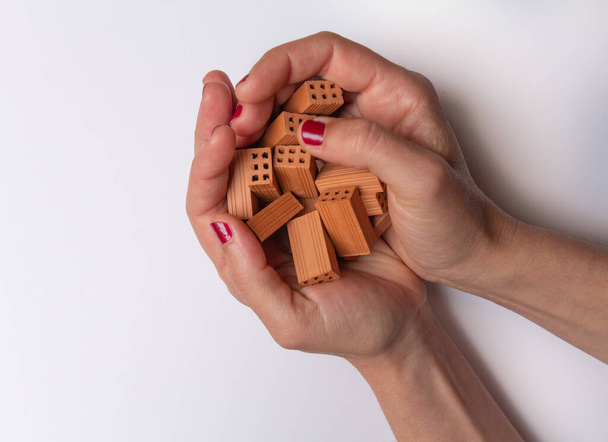 Δύο γυναικεία χέρια με πολλά μικρά τούβλα παιχνιδιού σε λευκό φόντο. - Φωτογραφία, εικόνα