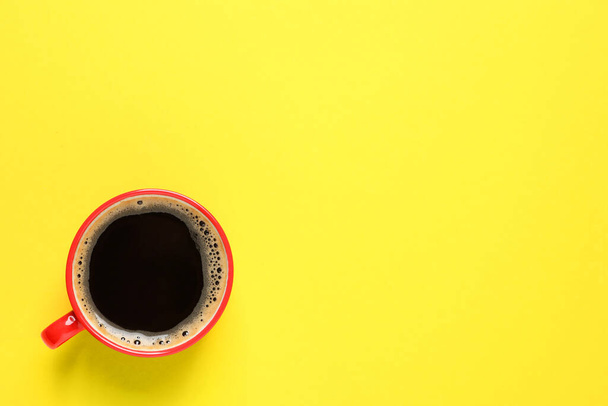 Aromatic coffee in red cup on yellow background, top view. Space for text - 写真・画像