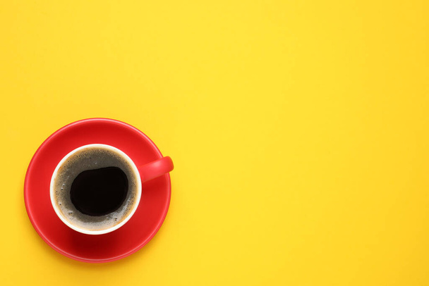 Aromatic coffee in red cup on yellow background, top view. Space for text - Фото, зображення