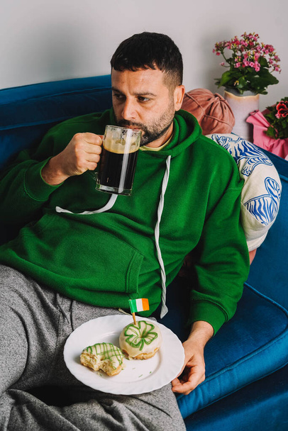 Un uomo single con ciambelle e robusto a colazione per festeggiare il giorno di San Patrizio - Foto, immagini