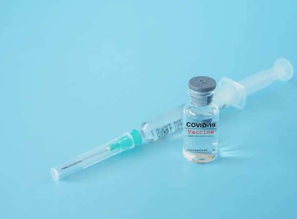 Großaufnahme, Impfflasche und Spritze auf blauem Hintergrund, mit Kopierraum. Konzept des Coronavirus-Ausbruchs. - Foto, Bild