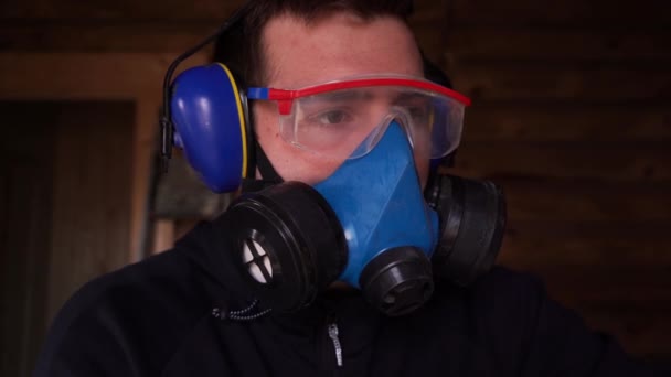 человек работает в респираторе, очки и наушники, чтобы защитить зрение, дыхание - Кадры, видео