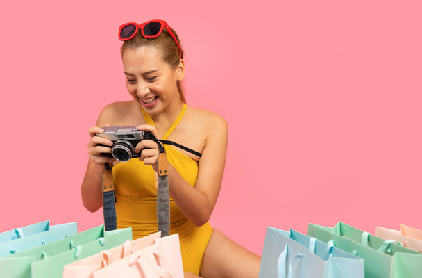 Beautiful, Sexy asian woman in  bikini and smiling standing on pink background isolated .Summer vocation happy trip.She smiling and  happy shopping bags. - Фото, зображення
