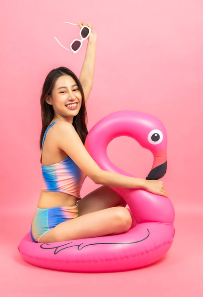 Belle Sexy femme asiatique en bikini et souriant debout sur fond rose isolé.. - Photo, image