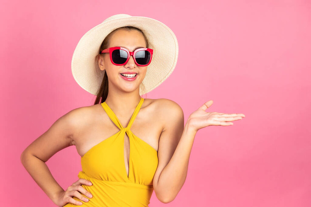 Beautiful Sexy asian woman in  bikini and smiling standing on pink background isolated .Summer vocation happy trip concept. - Foto, Imagen