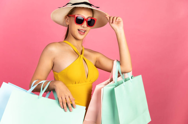 Beautiful, Sexy asian woman in  bikini and smiling standing on pink background isolated .Summer vocation happy trip.She smiling and  happy shopping bags. - Photo, image