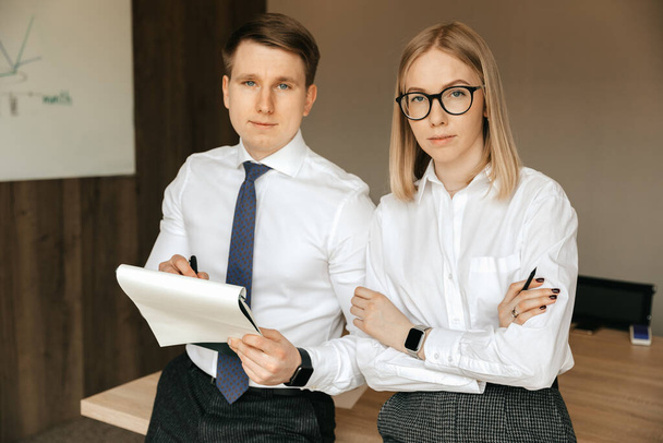 Successful office workers in the office. Businessman and businesswoman at the workplace with documents in hands.  - Foto, imagen