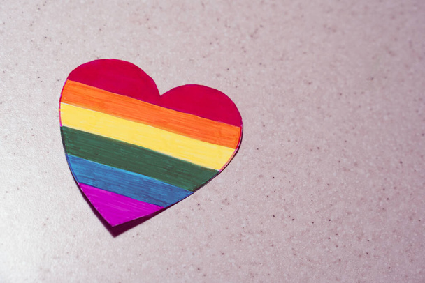 rainbow-colored hand-made heart on a pink background. Symbol of LGBTQ people and Month of pride concept - Photo, Image