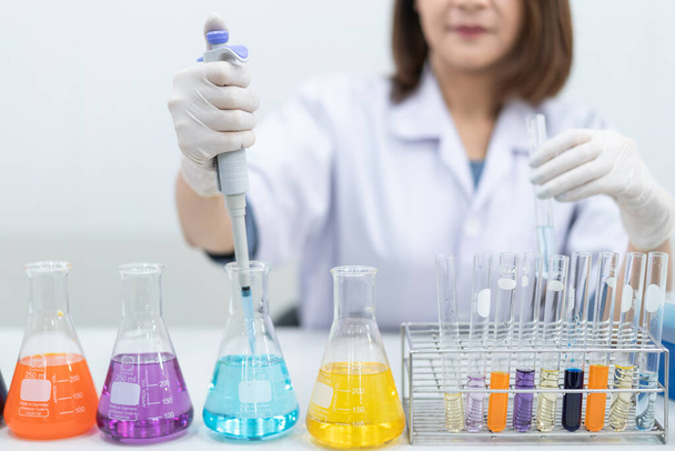 A young woman researcher, doctor, scientist, or laboratory assistant working with plastic medical tubes to research, examine scientific experiments in a modern laboratory. Education stock photo - Foto, Imagem