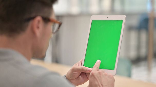 Middelbare leeftijd Man met behulp van tablet met groene chroma scherm  - Foto, afbeelding