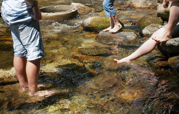 Group of people walking in forest river or cooling their bare feet, detail on legs only - Foto, Imagem