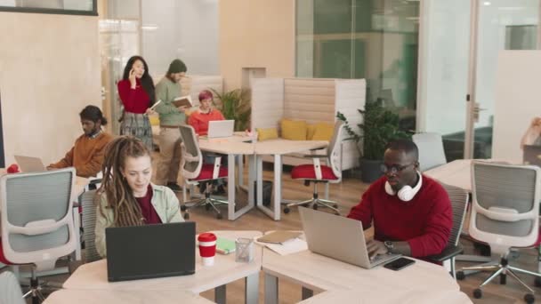 Plan de Slowmo d'un groupe d'hommes et de femmes d'affaires multiethniques travaillant dans un espace de coworking ou un bureau décloisonné - Séquence, vidéo