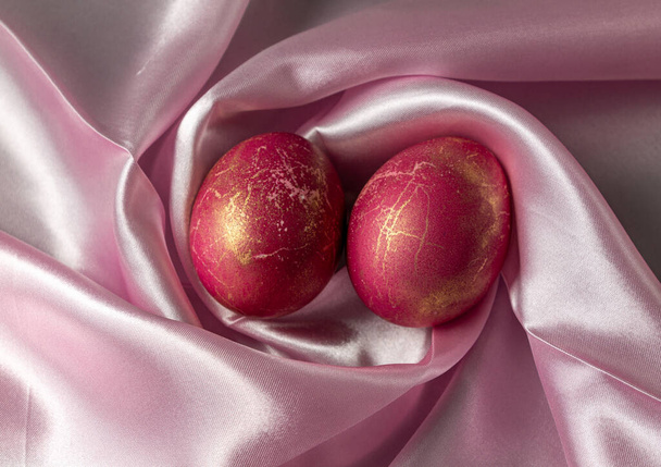 Dos huevos de pollo rojo yacen en una servilleta rosa. Vista superior de primer plano. - Foto, Imagen