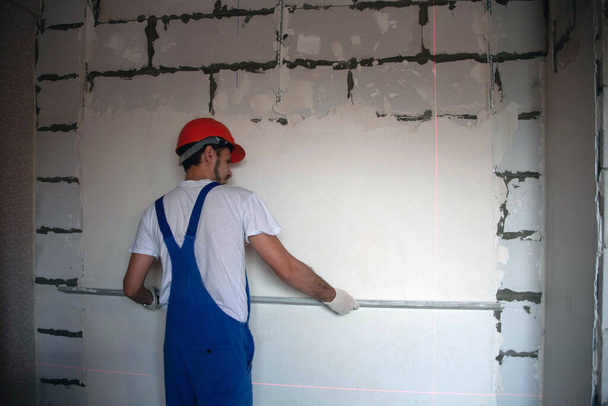 Bauarbeiter verputzt Fassade eines Hochhauses mit Spachtelmesser - Foto, Bild