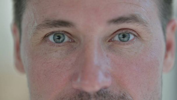 Sluiten van knipperende ogen van middelbare leeftijd man  - Foto, afbeelding