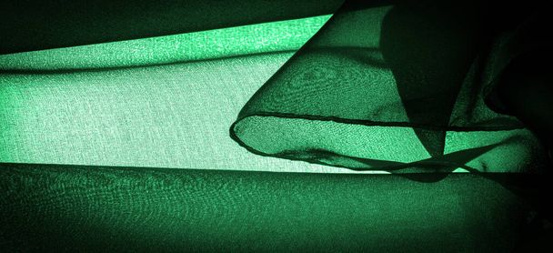 Achtergrondtextuur Donkergroene chiffon zijde is een zachte transparante stof met een lichte ruwheid (mat, gecrept) door het gebruik van gedraaid garen. - Foto, afbeelding