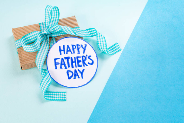 Ευτυχισμένη Ημέρα του Πατέρα. Μπλε ελάχιστο φόντο με δώσει μπαμπά ένα κουτί δώρο και μια κάρτα με την επιγραφή: Happy Fathers Day - Φωτογραφία, εικόνα