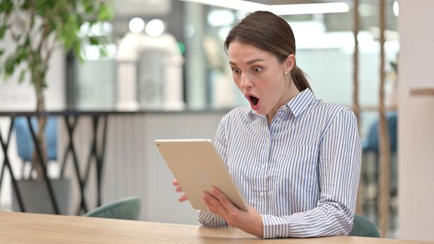 Dühös fiatal nő, amelynek elvesztése a digitális tabletta az irodában  - Fotó, kép