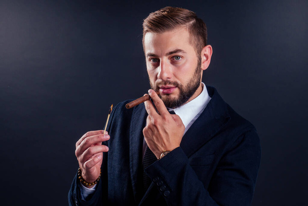 Portrait of an attractive business man with a cigar in black background studio - Valokuva, kuva