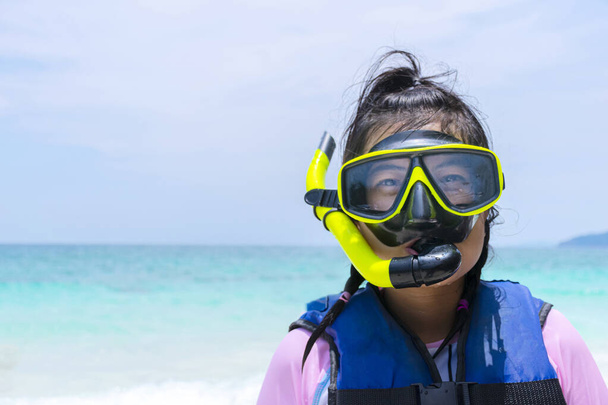 A cute Asian woman enjoying a snorkel mask at the beach on a sunny day, swimwear and a life jacket - Фото, изображение